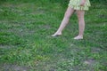 Detail of legs of young woman, in yellow dress, walking barefoot on the green grass, calm and relaxed. Spring concept, feet, grass Royalty Free Stock Photo