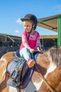 Detail of cute little girl preparing to ride a horse next to the stable Royalty Free Stock Photo