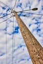 Detail looking up textured wood telephone pole with spotty clouds on blue sky Royalty Free Stock Photo