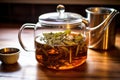 detail of loose leaf tea steeping in a clear glass teapot