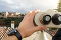 Detail of a man looking through the binoculars, sightseeing in Spain. Arab fortress, called the Alhambra in the background