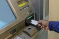 Detail of a man\'s hand inserting a blank card into an ATM