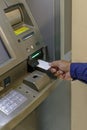 Detail of a man\'s hand inserting a blank card into an ATM