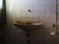 Detail from messy interior of abandoned building. Empty room with old dirty sink, cobweb and wall tiles Royalty Free Stock Photo