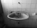 Detail from messy interior of abandoned building. Empty room with old dirty sink, cobweb and wall tiles Royalty Free Stock Photo