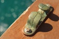 detail of a metal hook from the wooden side of a boat sailing in the blue sea