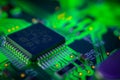 Detail of a microprocessor, resistors and capacitors soldered to a green glowing PCB Royalty Free Stock Photo