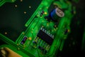 Detail of a microprocessor, resistors and capacitors soldered to a green glowing PCB Royalty Free Stock Photo