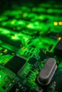 Detail of a microprocessor, resistors and capacitors soldered to a green glowing PCB Royalty Free Stock Photo