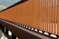 Detail of modern rusty orange colored pedestrian and bicycle bridge railing. Strong contrast of light and shadow, abstract