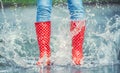 Detail of a moment when red polka dot rain boots jumped into a puddle of water, splashing all around Royalty Free Stock Photo