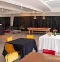 Detail of a multifunctional space with yellow chairs and tables in the foreground, a pool table in the background