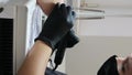 manicurist in black gloves paints nails in beige neutral color close-up beauty salon manicure process with gel polish