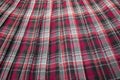 Detail of new fashion plaid pleated skirt: red, maroon, gray tartan school uniform fabric cotton/woolen material Royalty Free Stock Photo