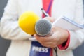 Female journalist at news conference, taking notes, holding microphone Royalty Free Stock Photo