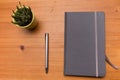 Detail of a notebook and small cactus on wooden table, minimalism