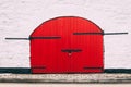 Detail of an old barn red door with black metal hinges against a white wall Royalty Free Stock Photo