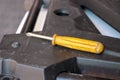 Detail of old mechanic yellow driver and on scratched black iron plate in automechanics workshop, close up. Royalty Free Stock Photo