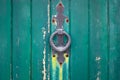 Detail of old teal wooden door with fleur-de-lis handle