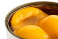 Detail of open can of peach halves in syrup on white. Royalty Free Stock Photo