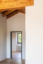 Detail of an open door, empty white room with exposed wood beams and hardwood floors Royalty Free Stock Photo