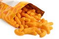 Detail of open packet of extruded cheese puffs spilling out on white Royalty Free Stock Photo