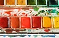 Detail of paint box showing half pans of red, yellow, and green watercolors Royalty Free Stock Photo