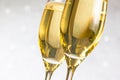 Detail of a pair of flutes of golden champagne on silver bokeh