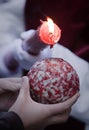Detail penitent red holding a candle pouring wax on a ball that holds a child in the hand during Holy Week