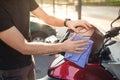 Detail of person cleaning the visor of his helmet on top of the motorcycle outdoors