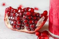 Detail photo - portion of pomegranate, cluster of gem like fruits visible, glass with pink smoothie on the right