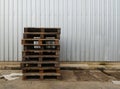 Pile of old wood pallet on dirty ground in front of steel wall in industry Royalty Free Stock Photo