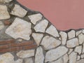 Detail of a pink wall with stones in various shades of beige.