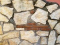 Detail of a pink wall with stones in various shades of beige.