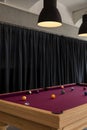 Detail of a pool table with balls and large lamps to illuminate the scene. In the background there are black curtains Royalty Free Stock Photo