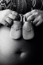 Detail of pregnant woman holding baby shoes against her belly. Bw version