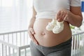 Close up of pregnant woman holding a pair of baby shoes