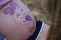 Detail of a pregnant woman`s belly with paint. It is a baby shower party and they are painting a picture of a baby on the pregnan