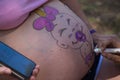 Detail of a pregnant woman`s belly with paint. It is a baby shower party and they are painting a picture of a baby on the pregnan
