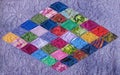 Detail of quilt sewn from multi-colored rhombus on a lilac background
