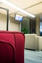 Detail of red suitcase in the airport waiting room. Screen with information of departures in the background Royalty Free Stock Photo