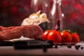 Detail of red tomatoes next to pork tenderloin on wooden board Royalty Free Stock Photo