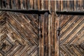 Detail of rustic old wooden barn doors of rough and weathered planks with rusted iron hinge and lock