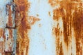 Detail of a rusty door on rusty hinges.Rust background with scratches and remnants of blue paint Royalty Free Stock Photo