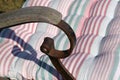 Detail of rusty metal iron chair with wooden handles in the garden close up with striped pillow in sunlight close up