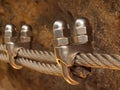 Detail of clamp at end of irone rope. Climbers iron twisted rope fixed in block by screws snap hooks anchored into rock. Royalty Free Stock Photo