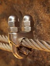 Detail of clamp at end of irone rope. Climbers iron twisted rope fixed in block by screws snap hooks anchored into rock. Royalty Free Stock Photo