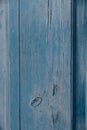 Detail of a section of wooden, blue, painted fence boards with cracks and grain