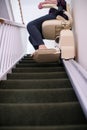 Detail Of Senior Woman Sitting On Stair Lift At Home To Help Mobility