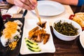 Detail of several Asian food dishes in a restaurant and a girl in the background out of focus eating with chopsticks Royalty Free Stock Photo